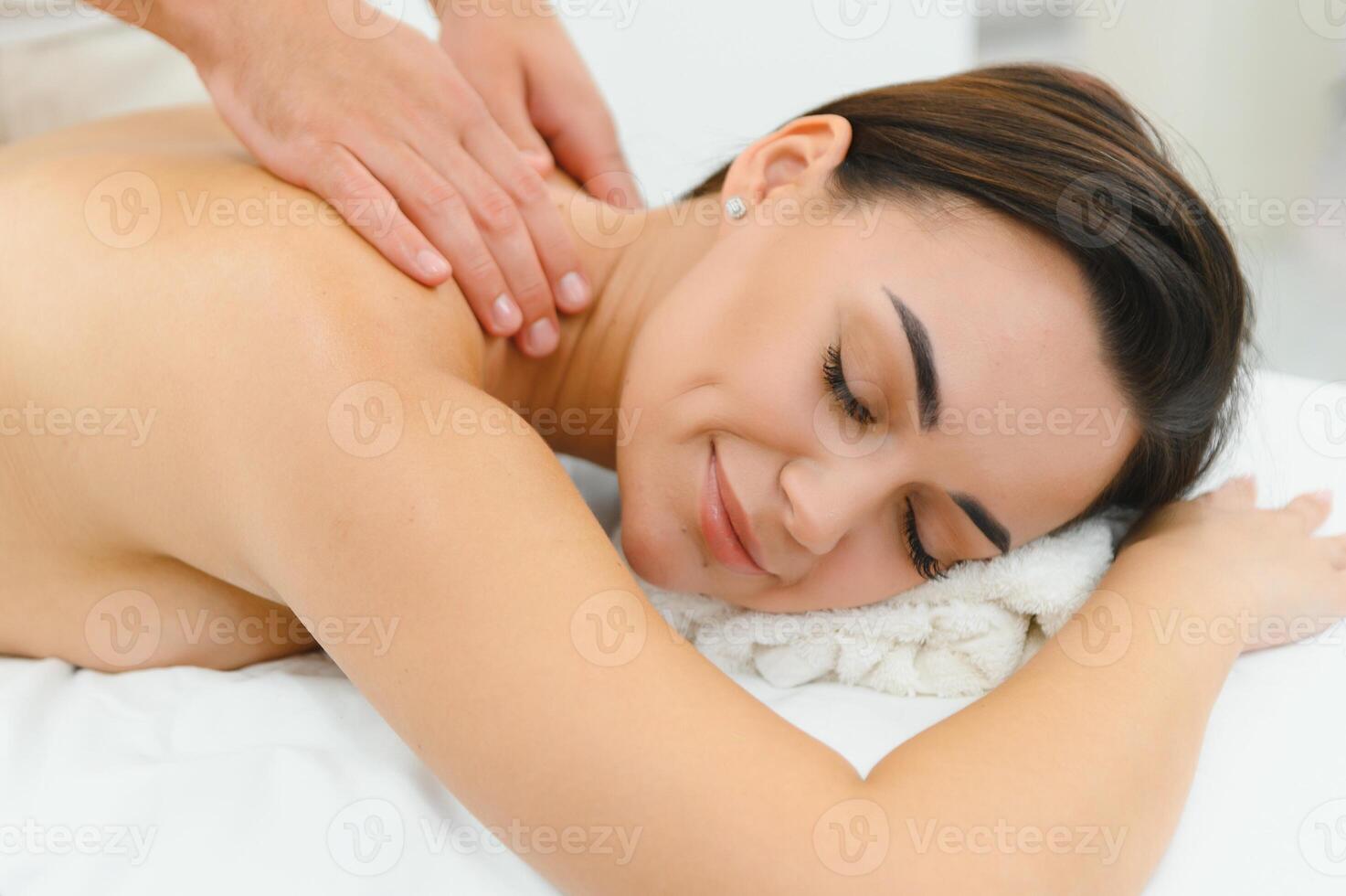 Osteopath massaging back of woman lying on front in health spa photo