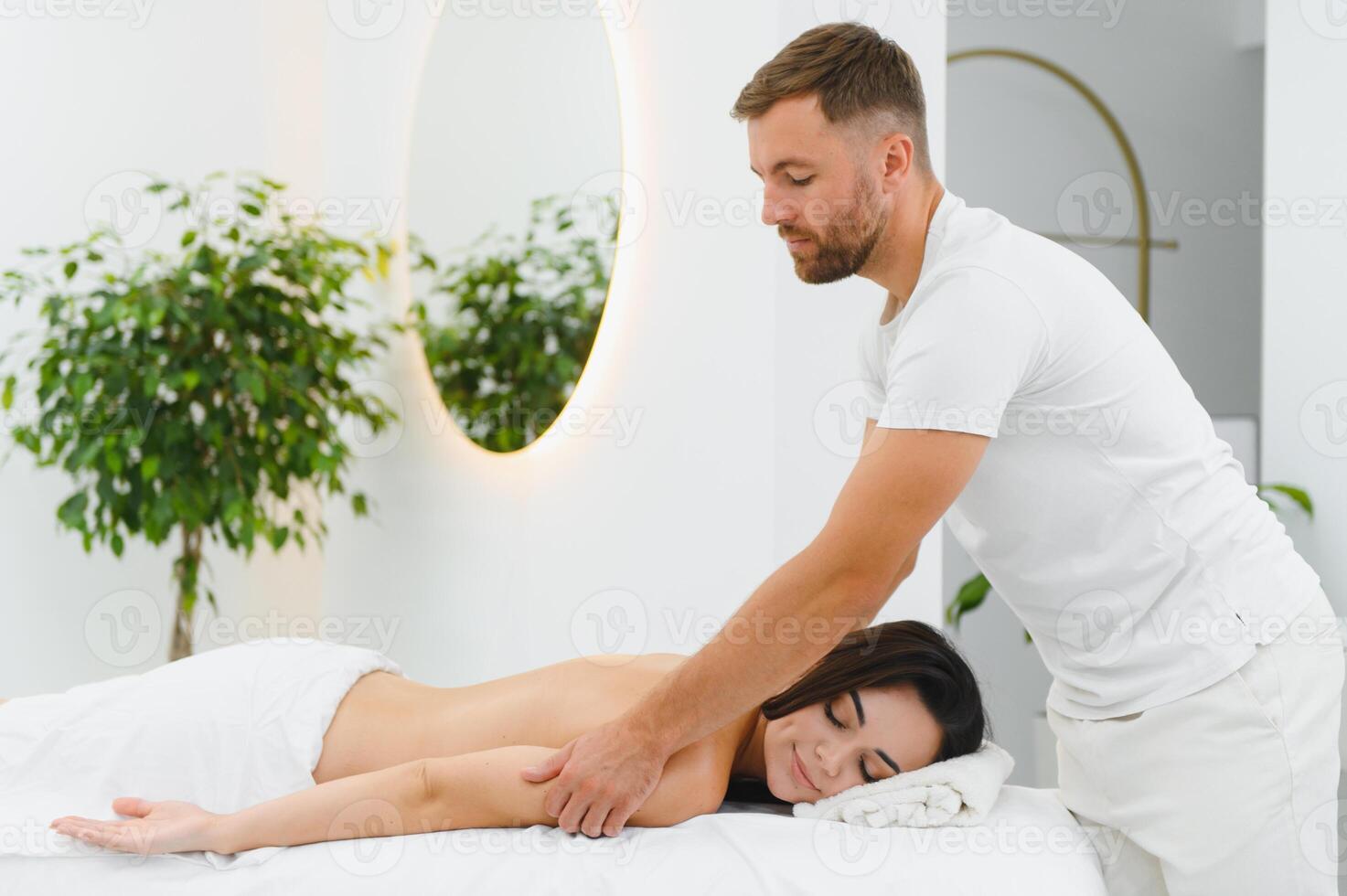 Young woman getting back massage in spa salon photo