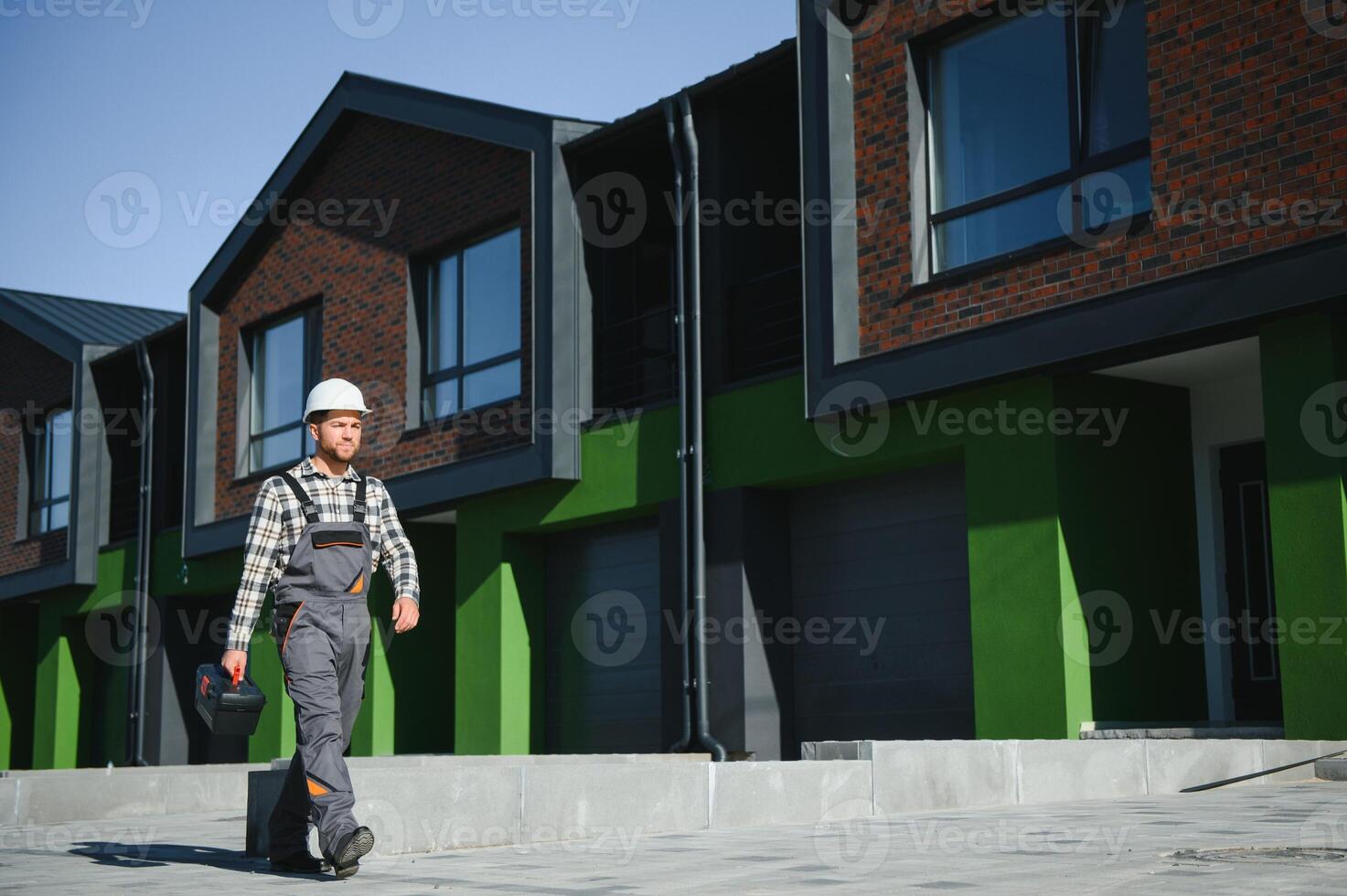 Master on call. A plumber or builder is standing near a house. photo