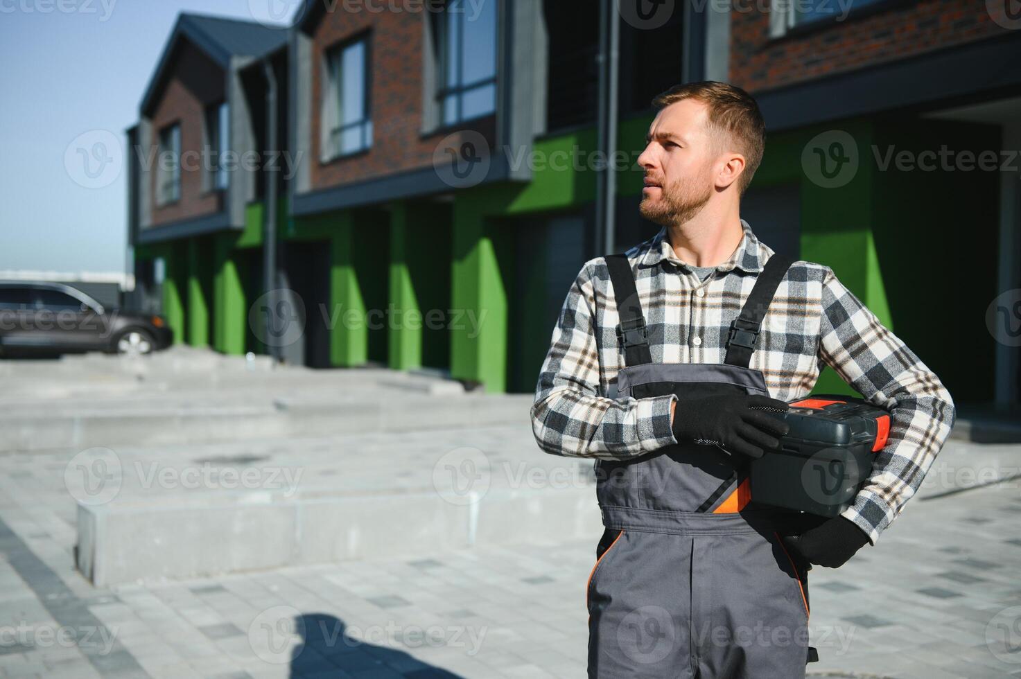 Master on call. A plumber or builder is standing near a house. photo