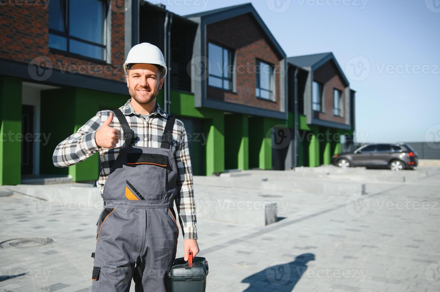 Master on call. A plumber or builder is standing near a house. photo