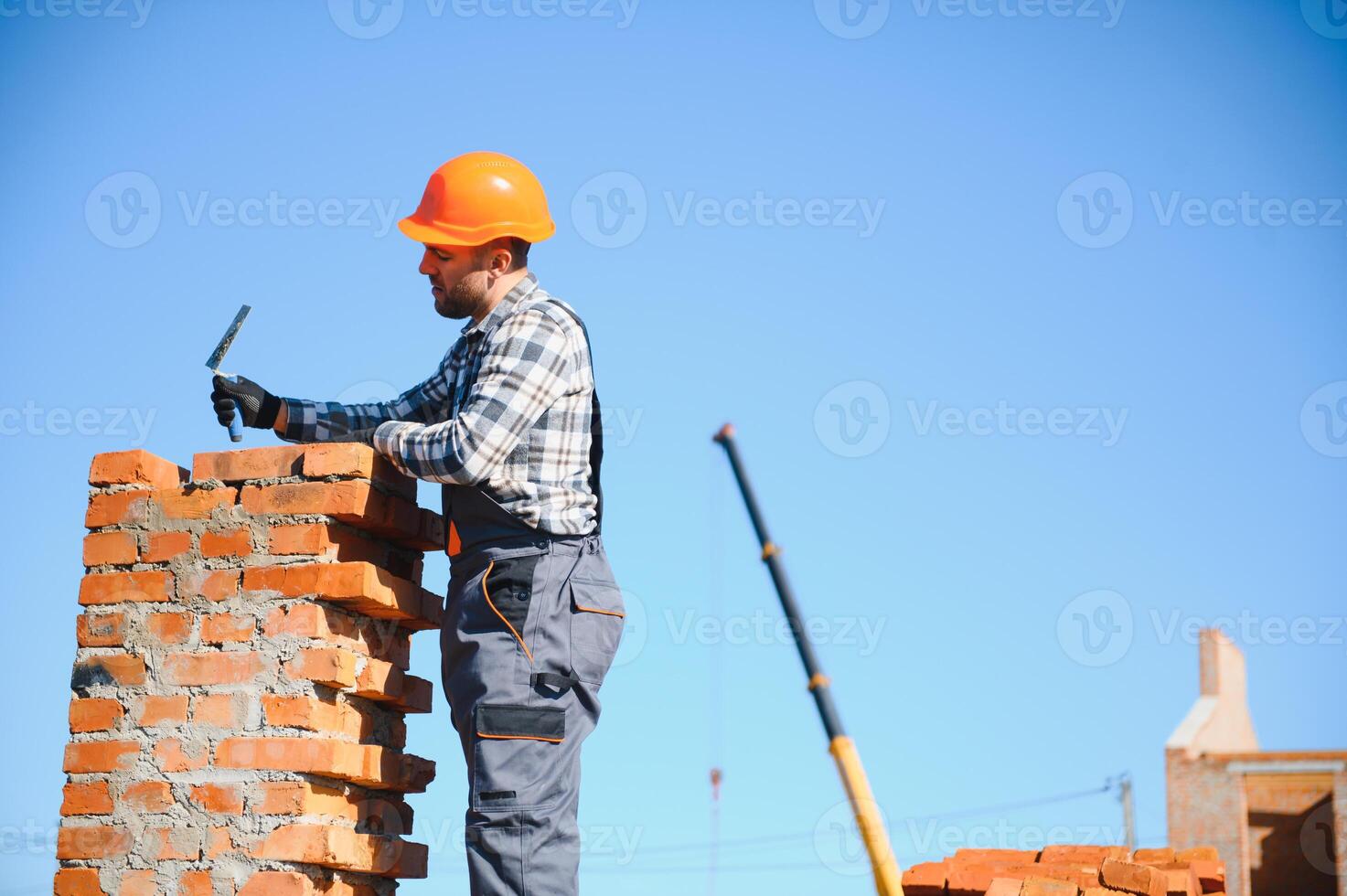 Installing brick wall. Construction worker in uniform and safety equipment have job on building photo