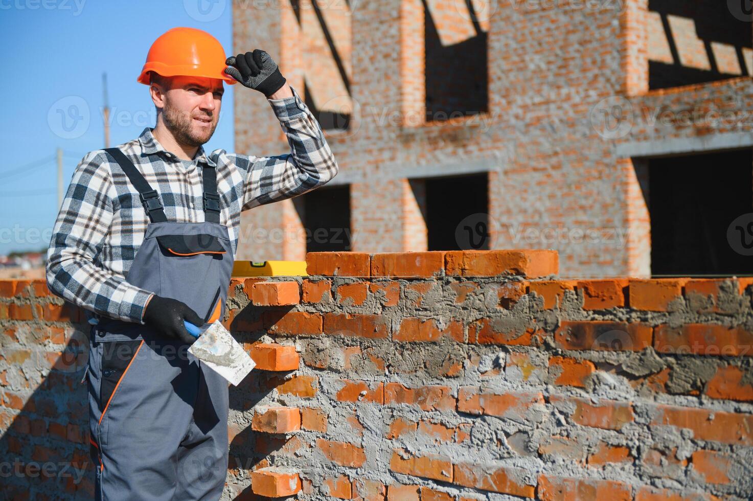Installing brick wall. Construction worker in uniform and safety equipment have job on building photo