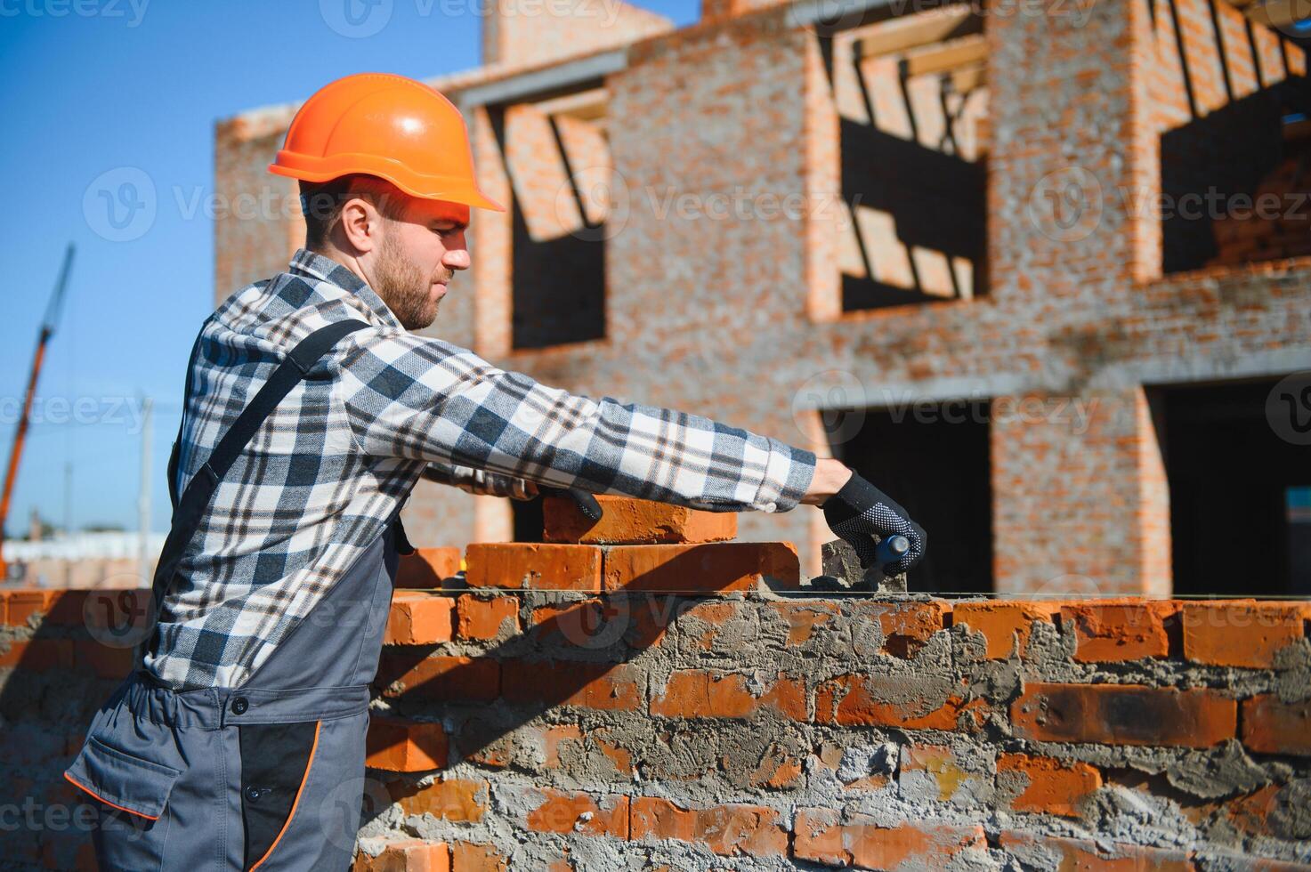Installing brick wall. Construction worker in uniform and safety equipment have job on building photo