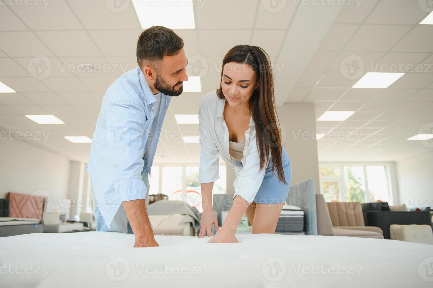 A married couple chooses a new bed for the bedroom and an orthopedic mattress in a furniture store photo