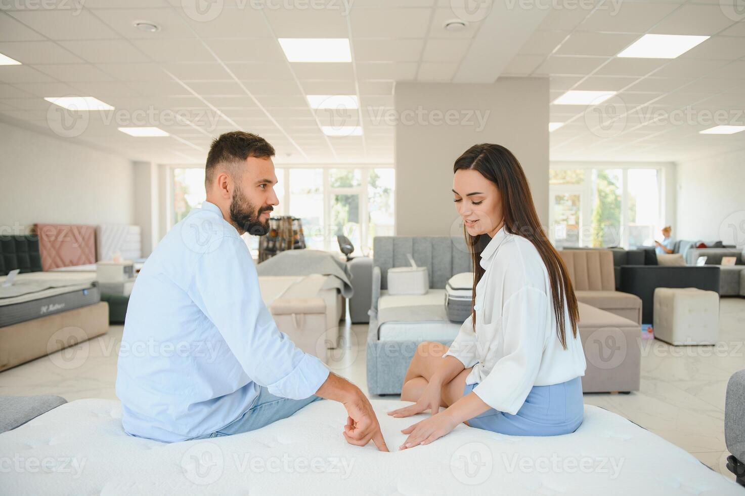 A beautiful young couple chooses a new mattress in a store photo