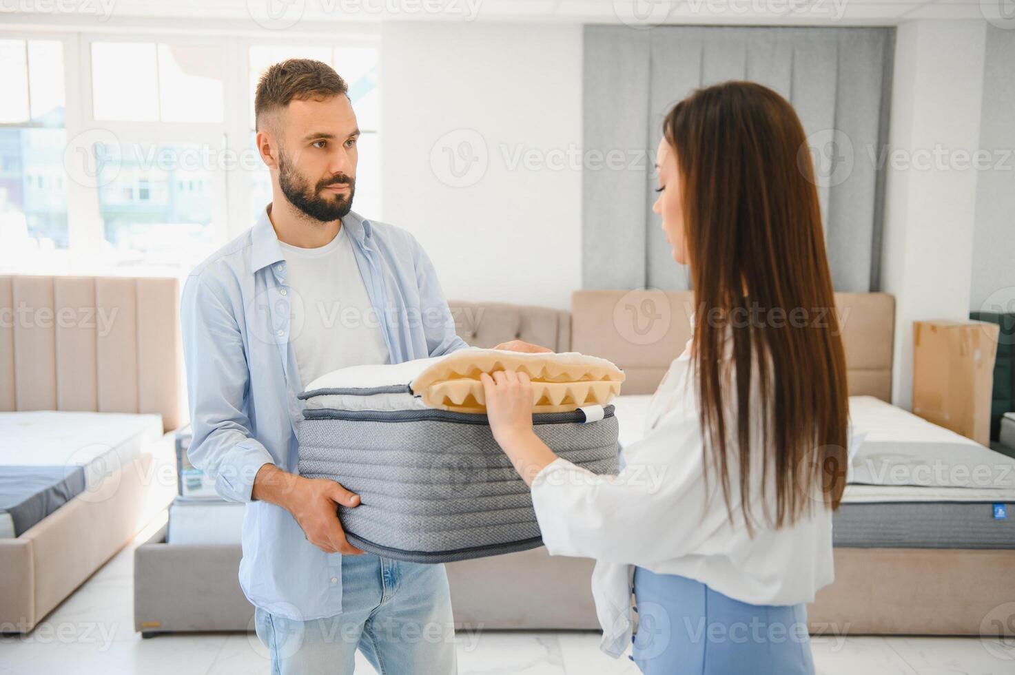 A married couple chooses a new bed for the bedroom and an orthopedic mattress in a furniture store photo