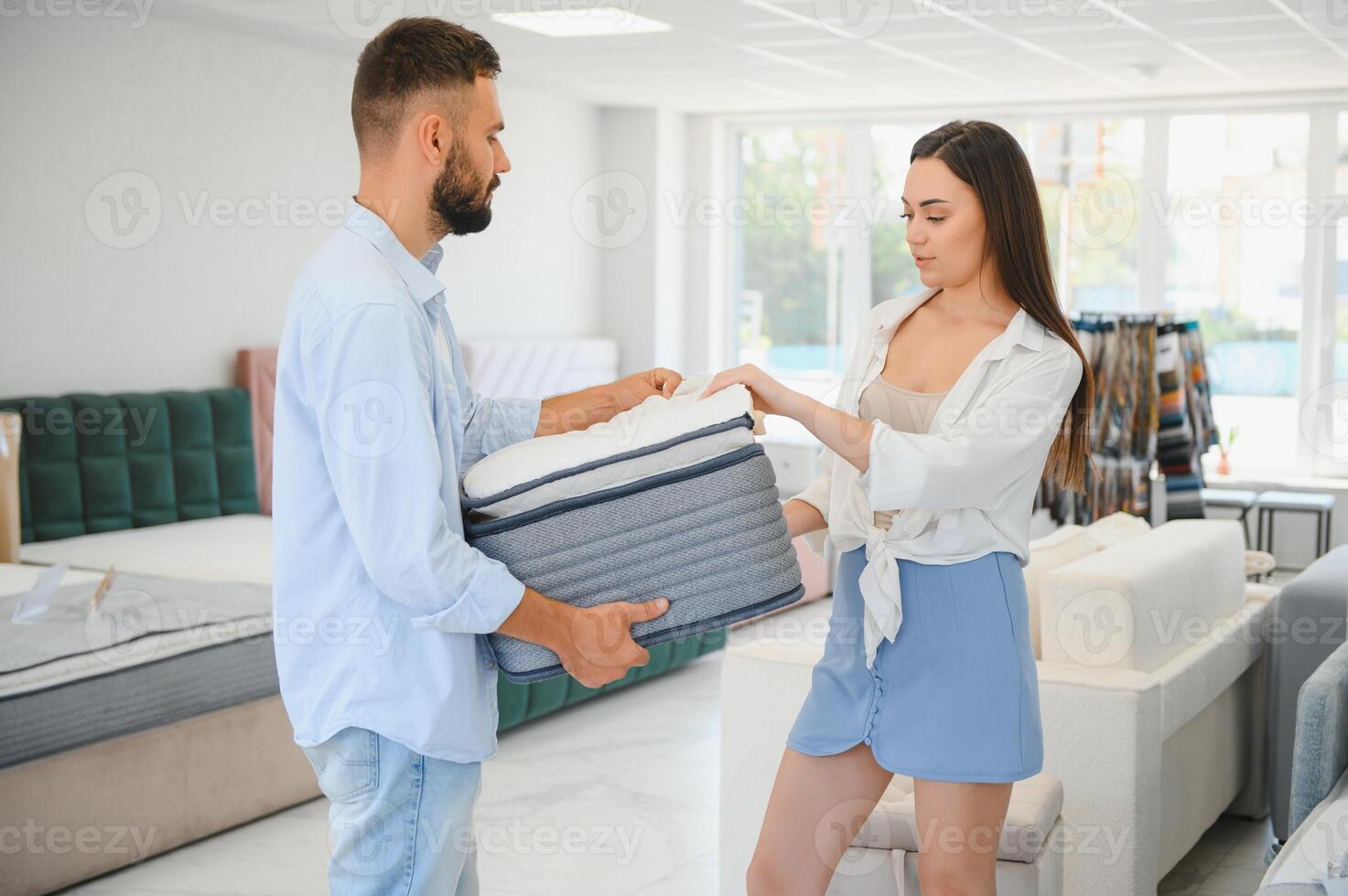 A beautiful young couple chooses a new mattress in a store photo