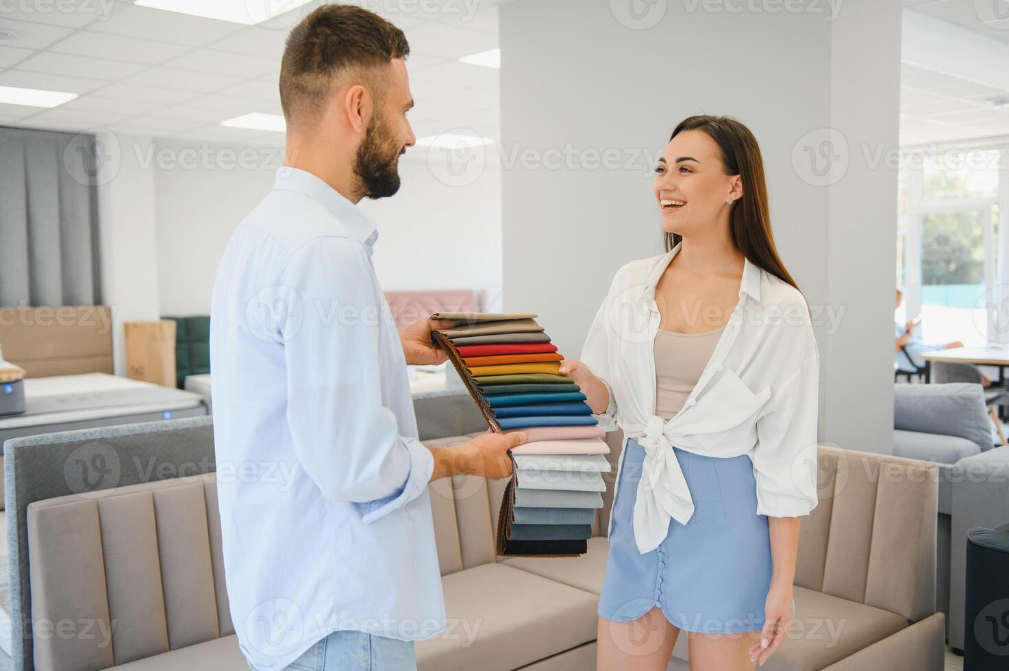 Couple choose soft corner in furniture store. Husband examines set of upholstery fabric samples photo
