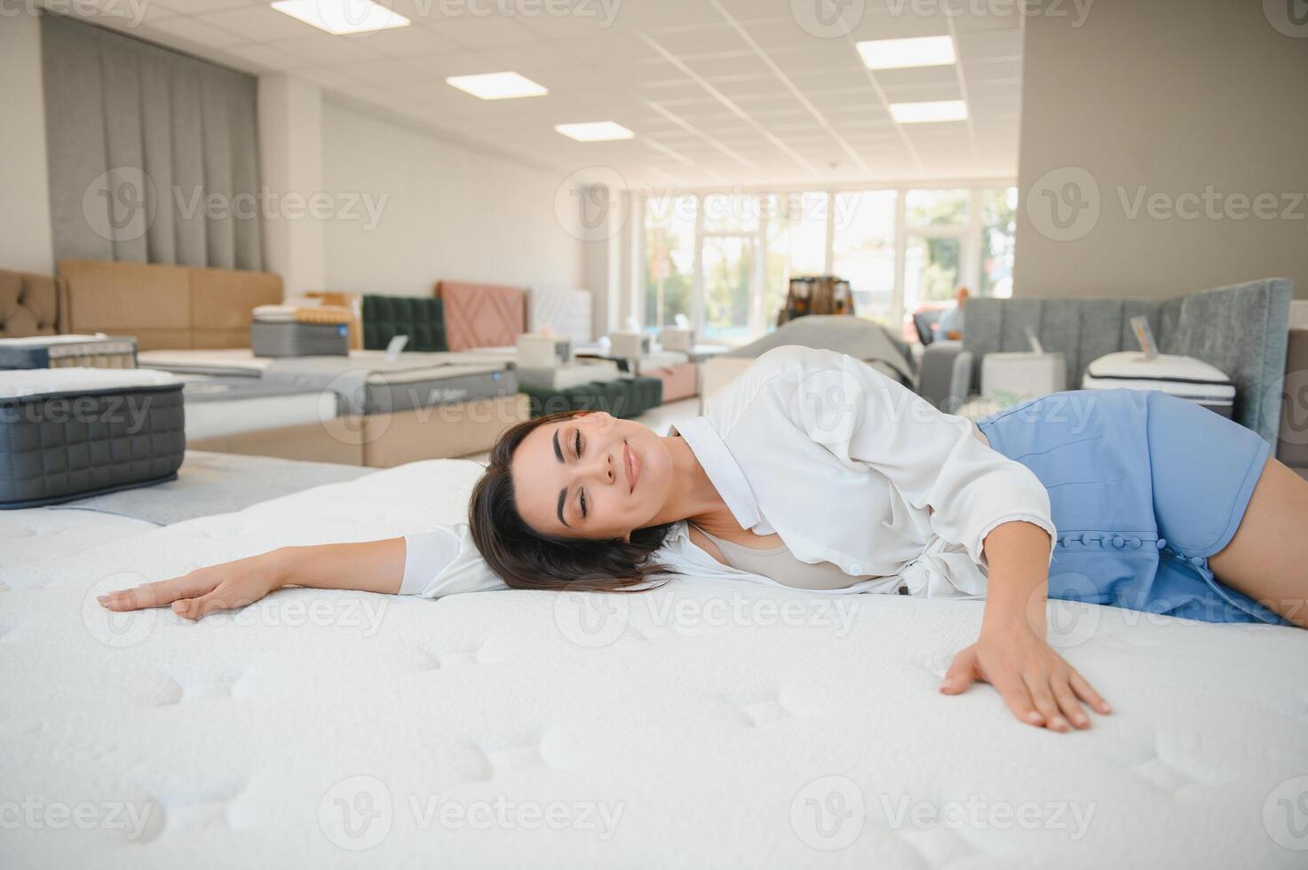 A woman in a white shirt in a mattress store. She examines the mattress she wants to buy photo