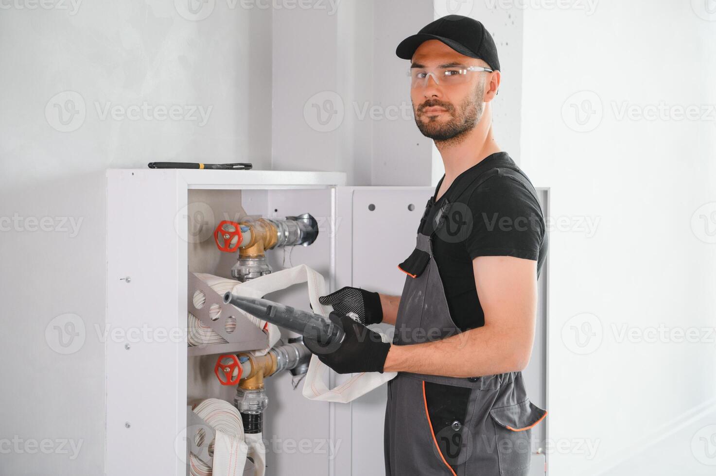 The worker installs or inspects Fire extinguisher and fire hose reel in building corridor photo