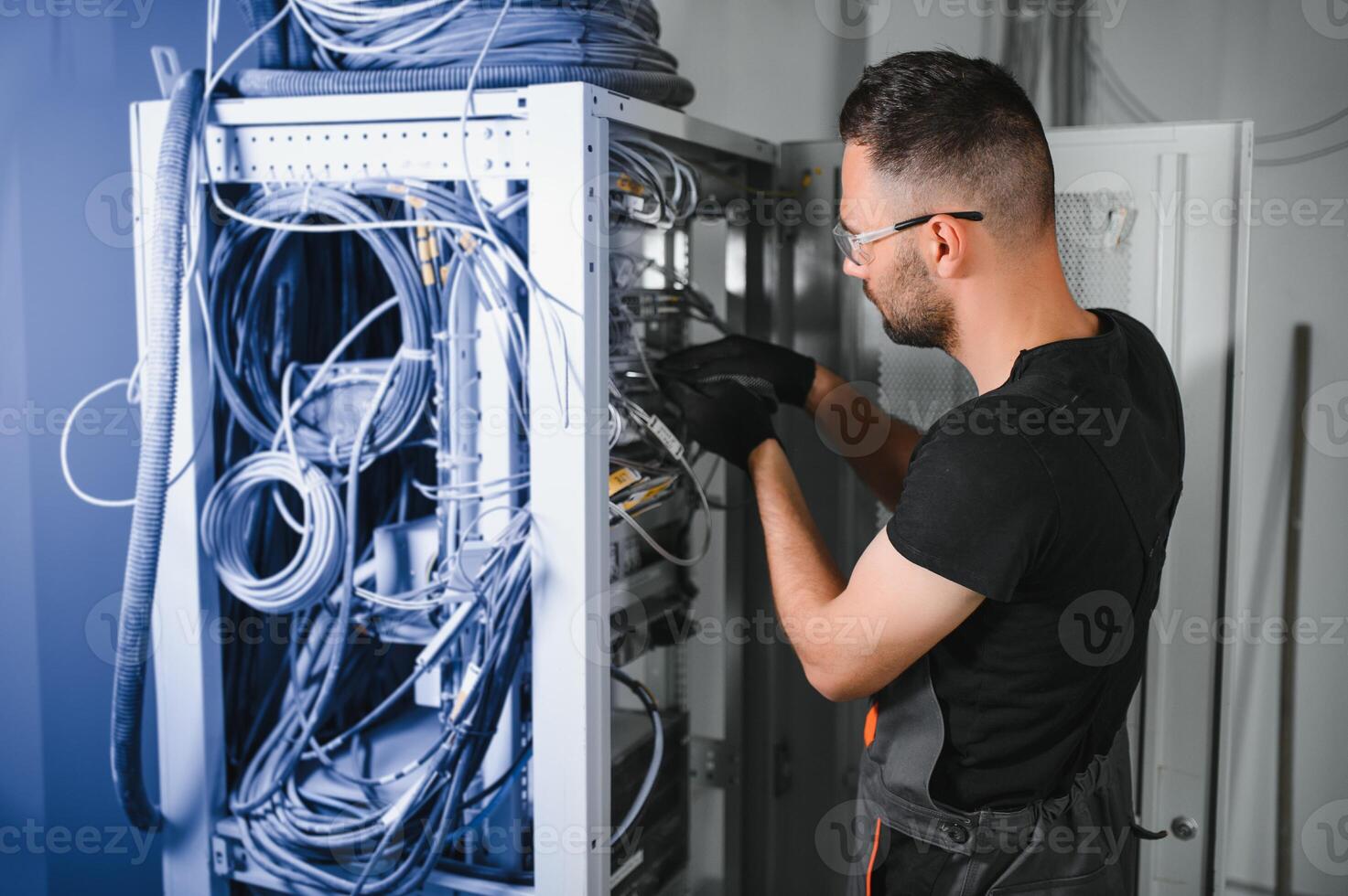 Repairman is busy and working with internet equipment and wires in server room photo