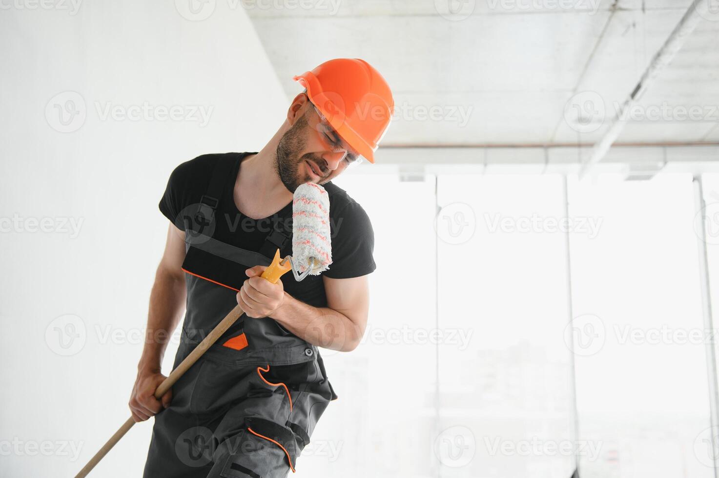 Funny and cheerful worker sings in a roller for painting the walls photo