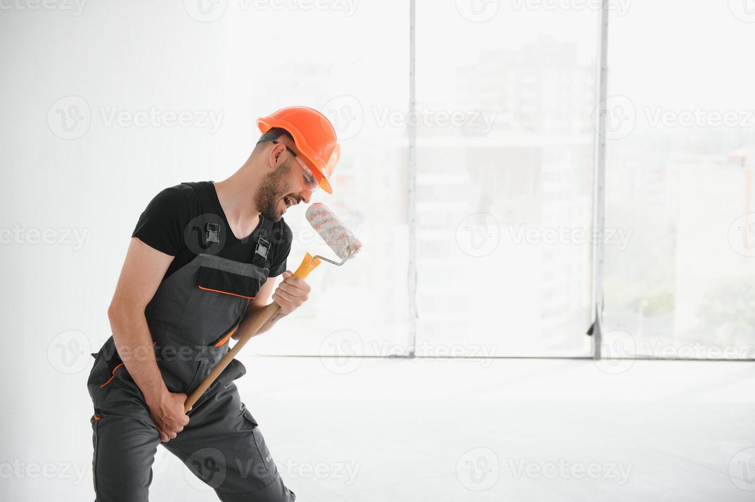 Funny and cheerful worker sings in a roller for painting the walls photo