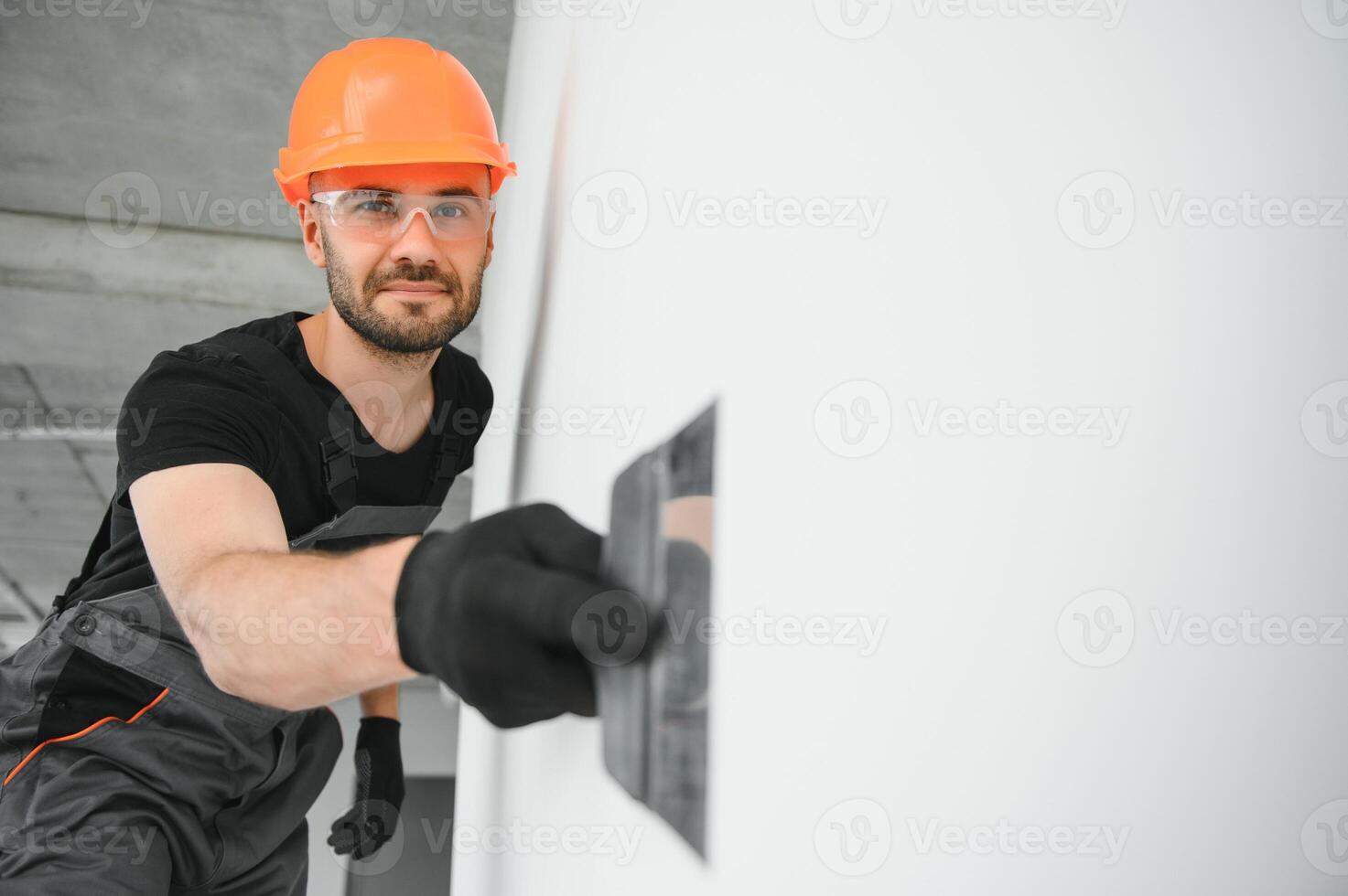 Tradesman on stilts plastering drywall in home photo