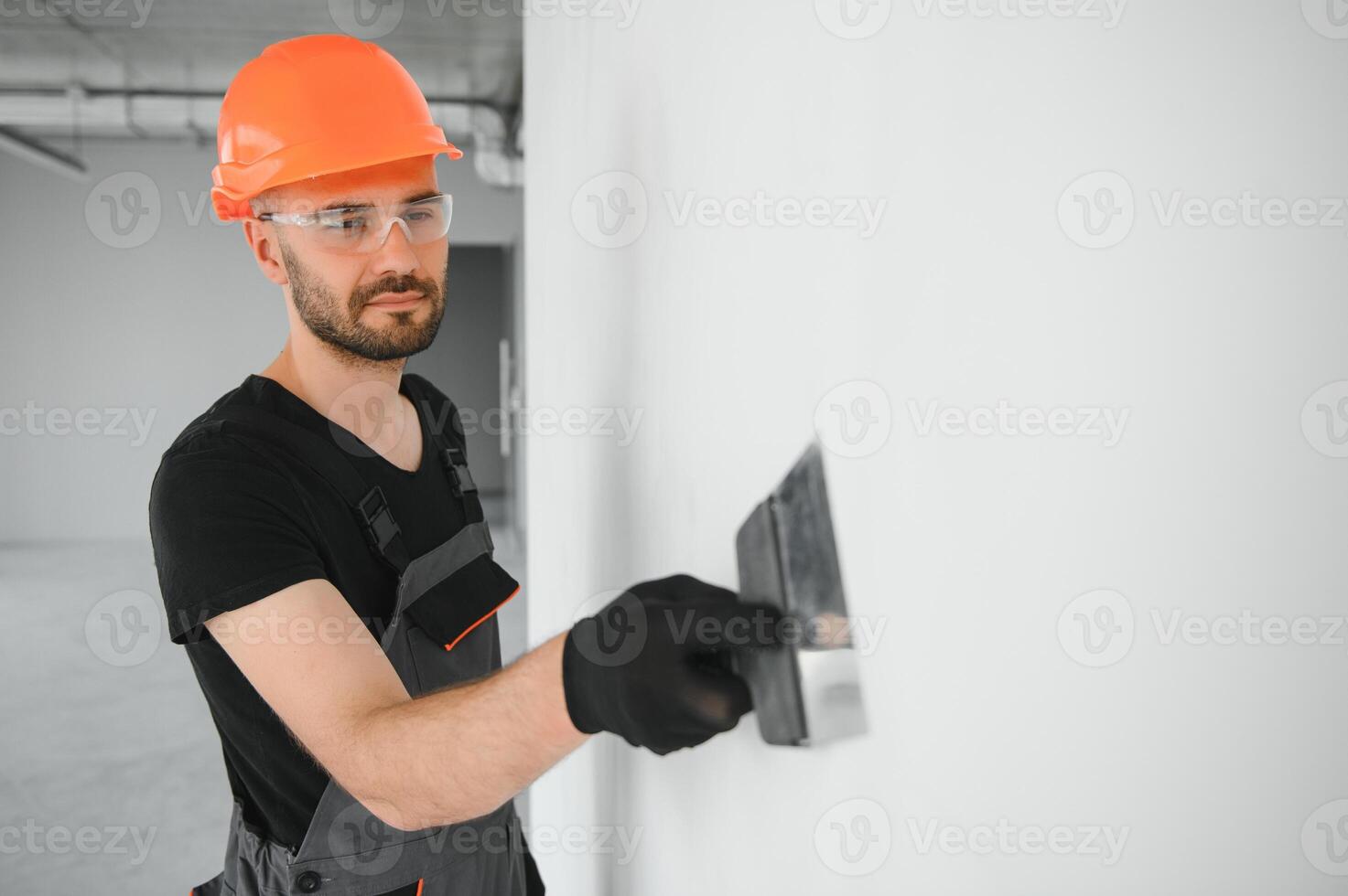 Professional worker plastering wall with putty knife indoors photo