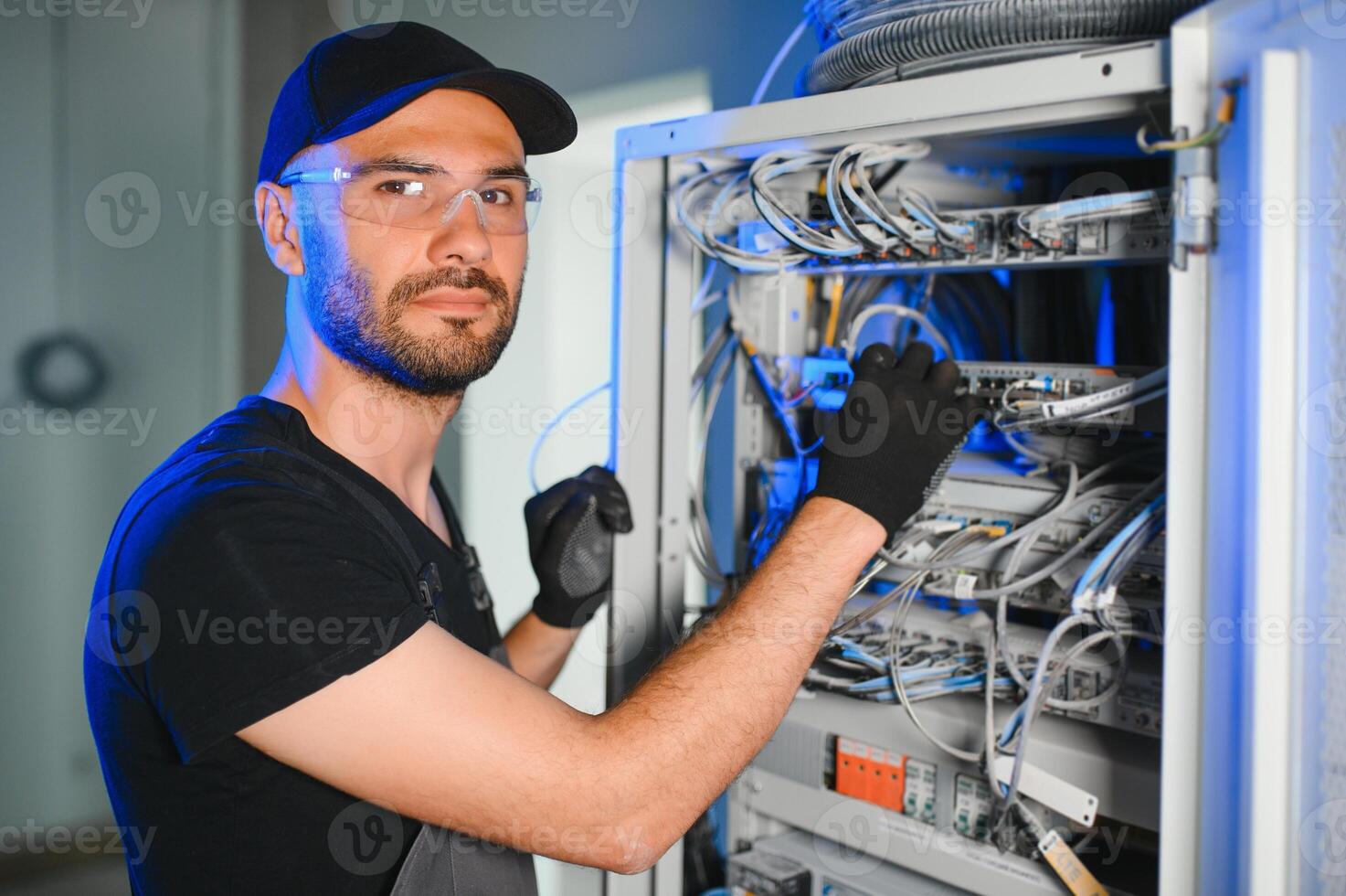 Repairman is busy and working with internet equipment and wires in server room photo