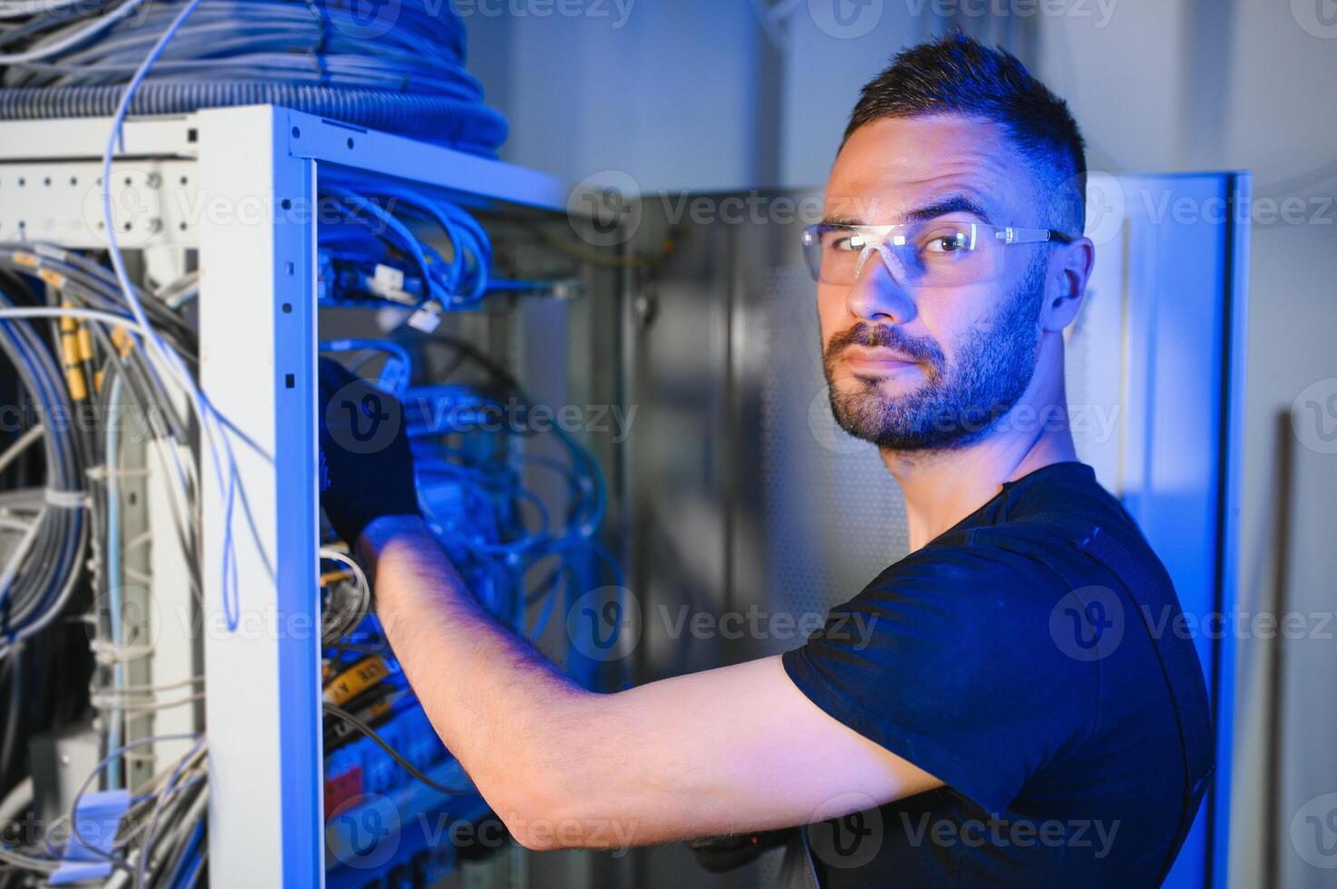 Repairman is busy and working with internet equipment and wires in server room photo