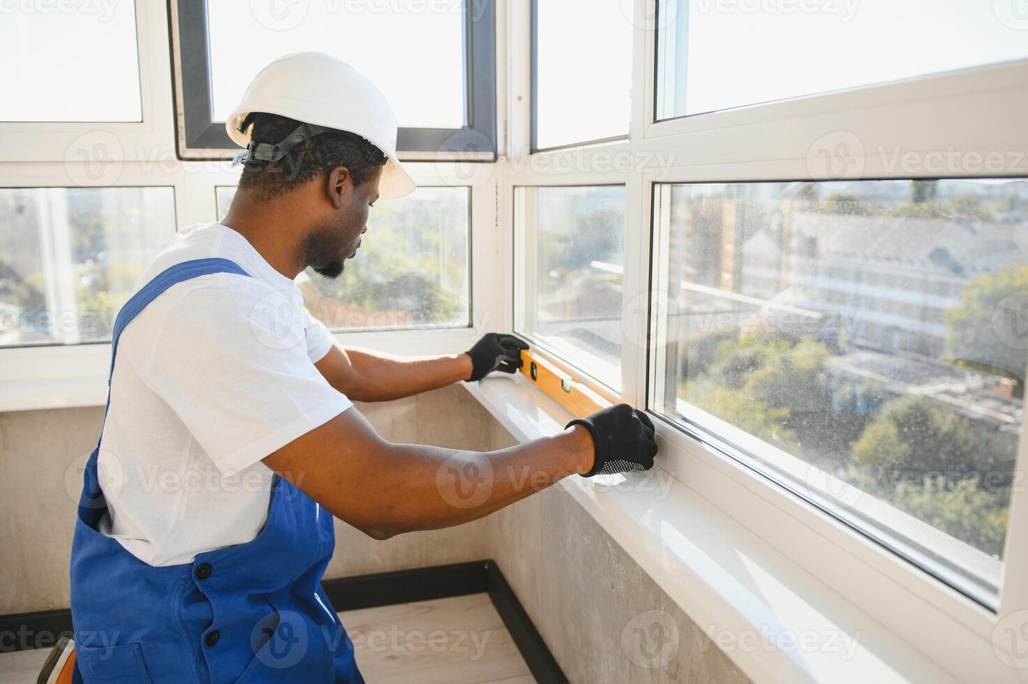 Worker in installing white plastic upvc window on house photo