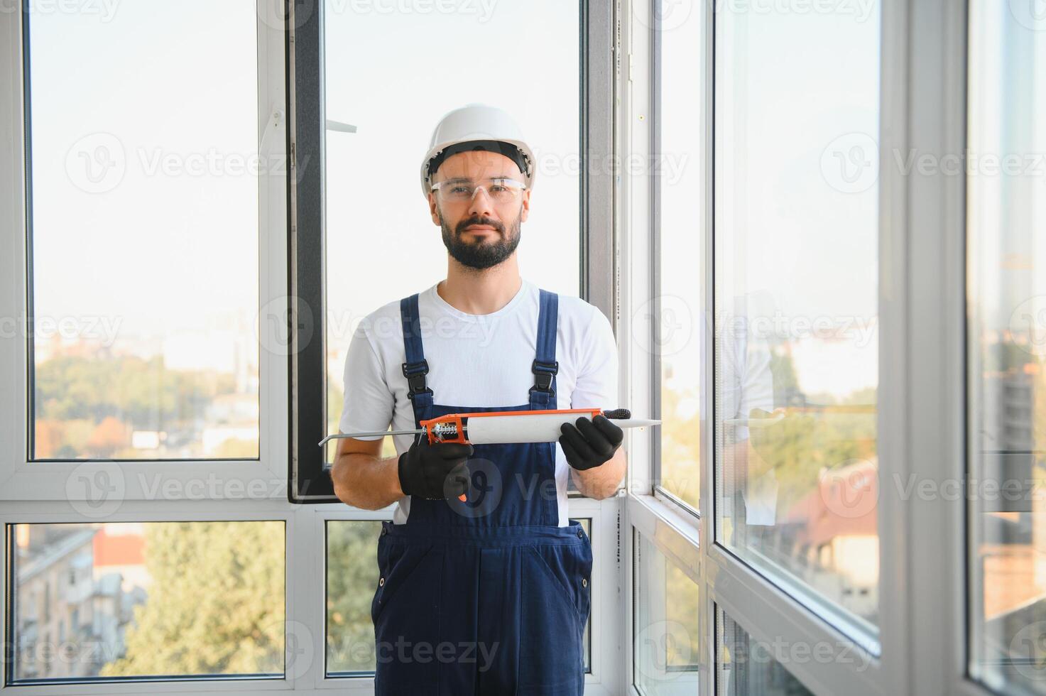 Workman in overalls installing or adjusting plastic windows in the living room at home photo