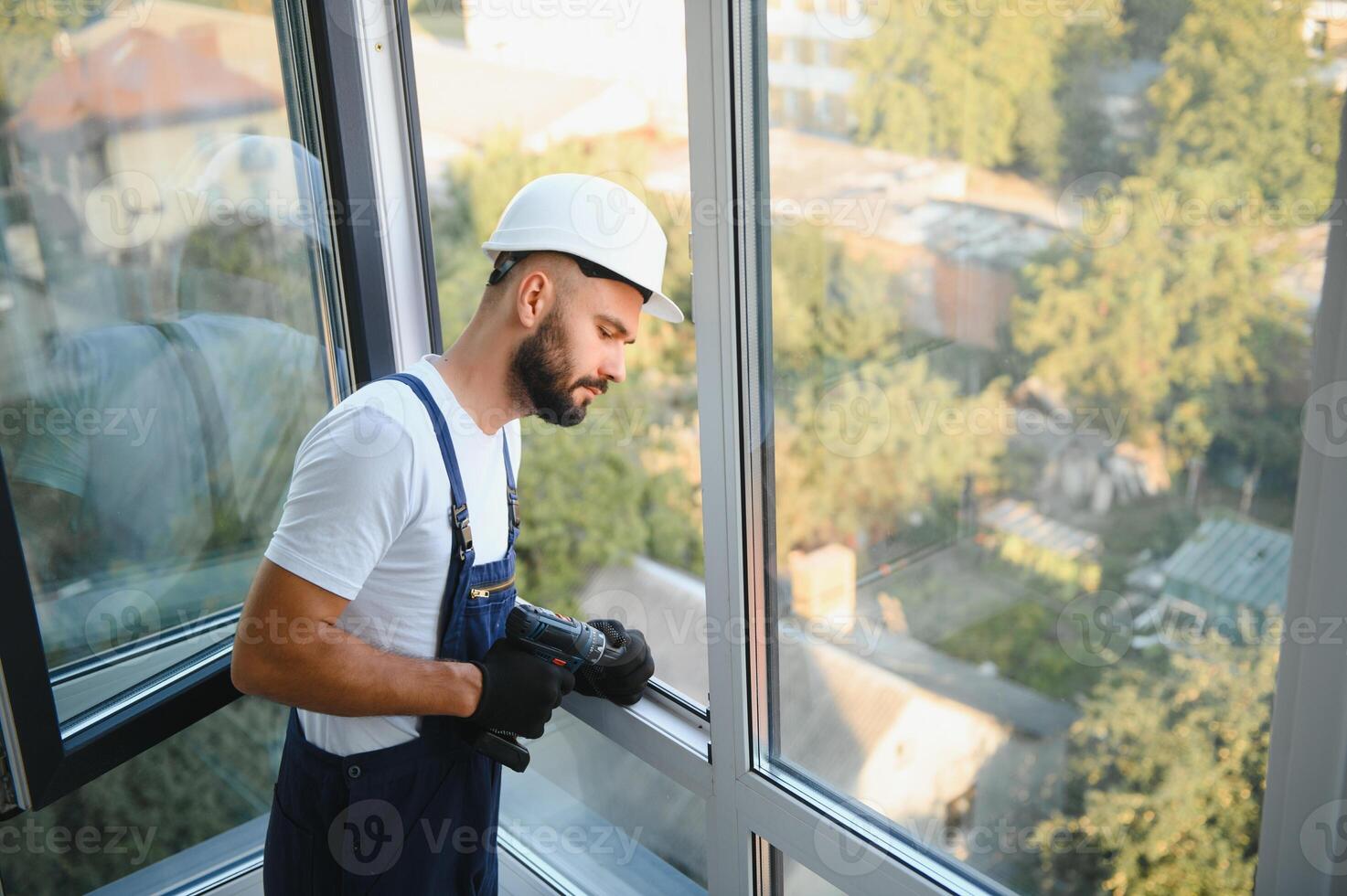 handyman adjusting white pvc plastic window indoors. worker using screwdriver to repair upvc window. homework maintenance photo