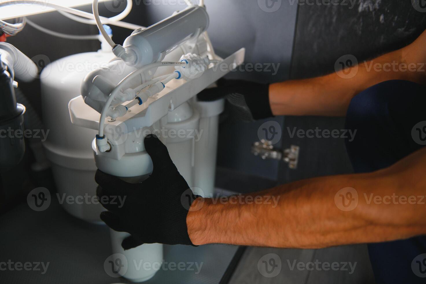 Plumber working install new cartridge for cold water filter in white kitchen photo