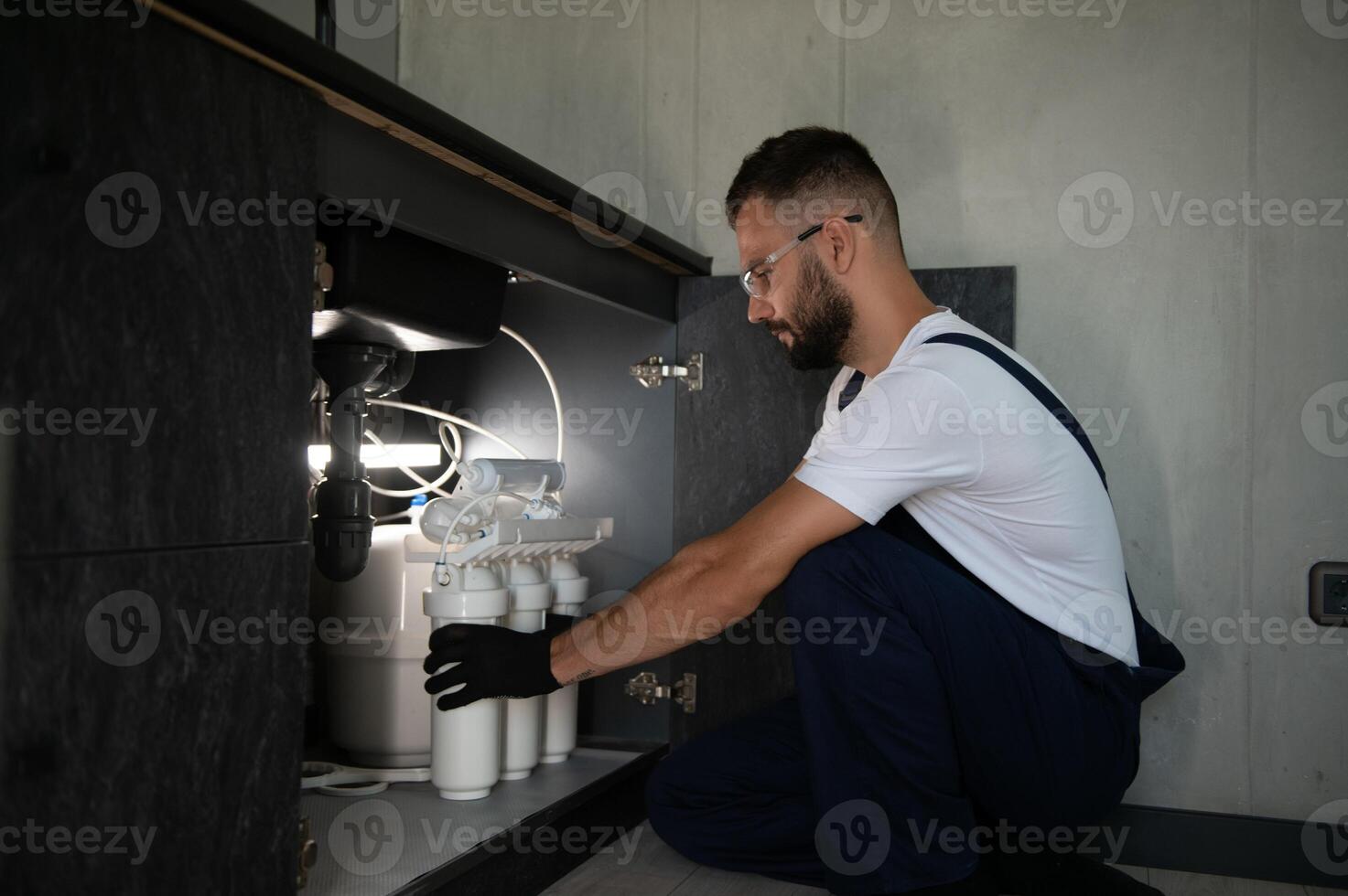 Plumber working install new cartridge for cold water filter in white kitchen photo