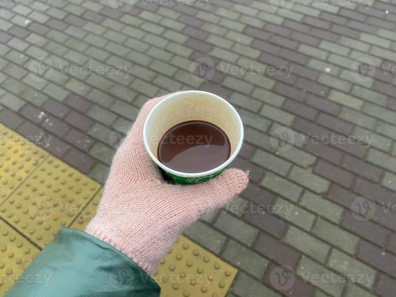 A gloved hand holds a cup of hot beverage photo