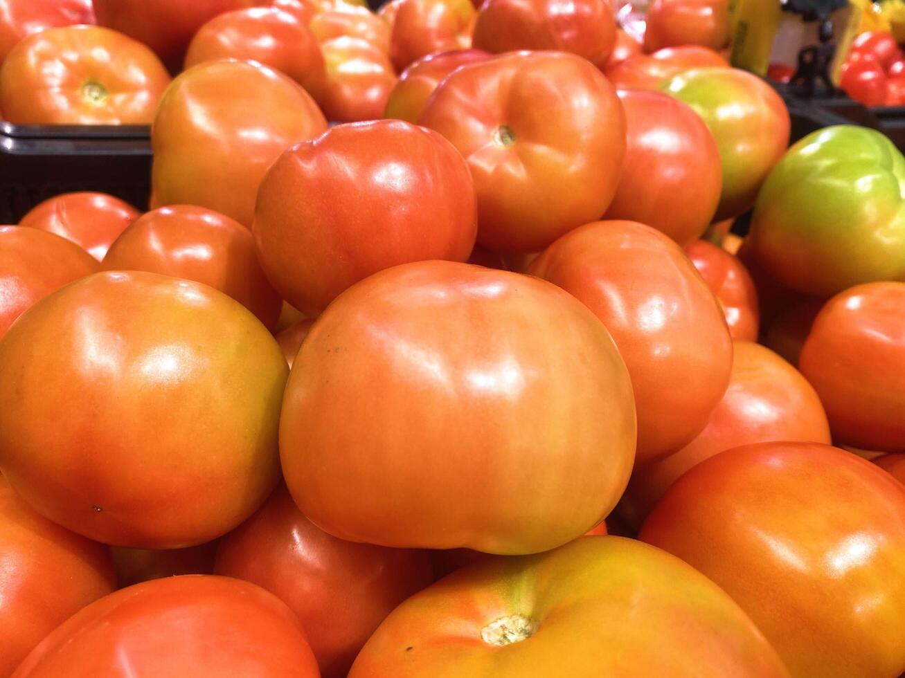 A stack of tomatoes in a market or grocery store window photo