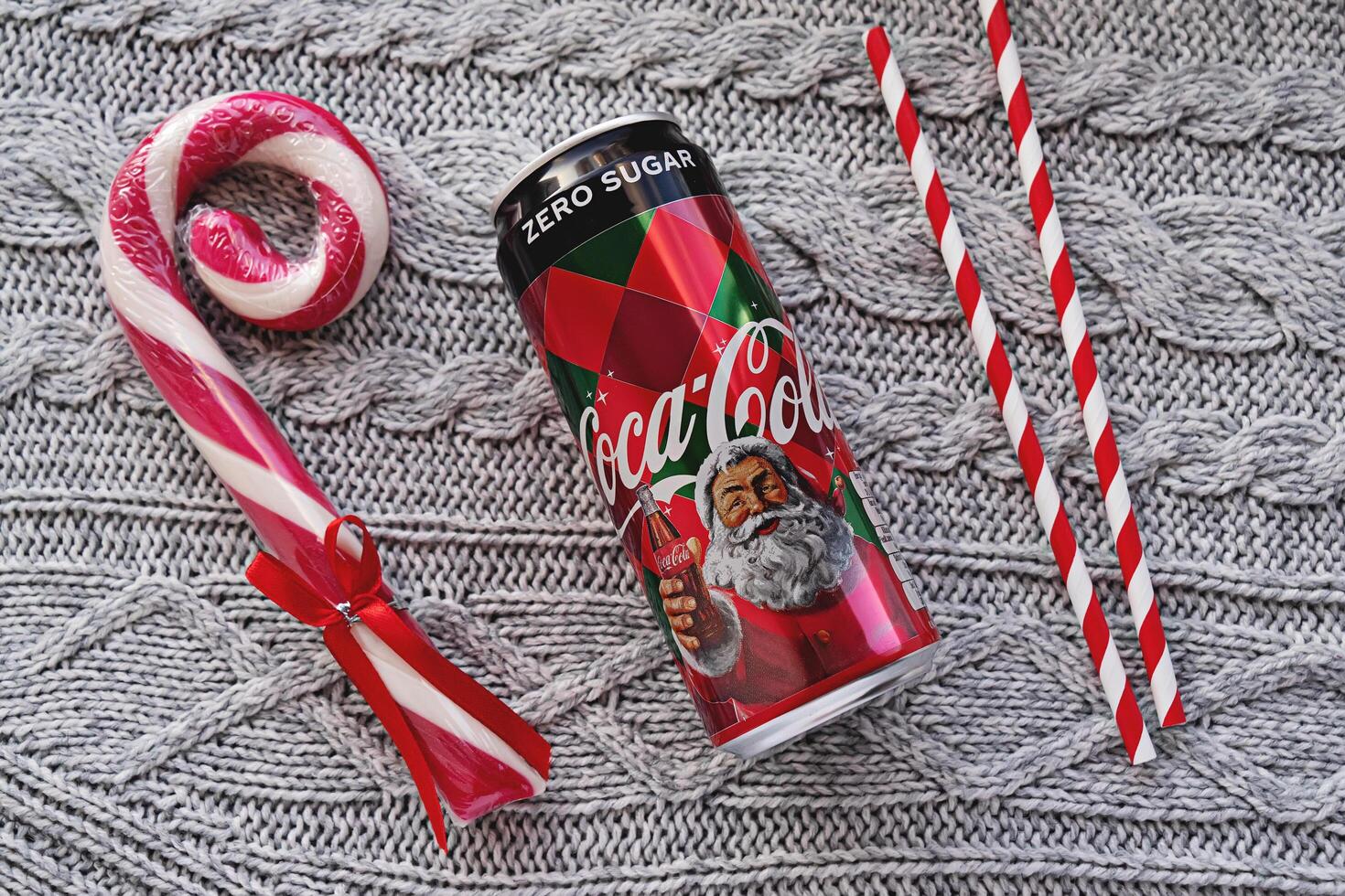 Tallinn, Estonia-30.11.2019 - Festive Holiday Drink Can with Gold Cup and Striped Straws on Gray Fabric photo