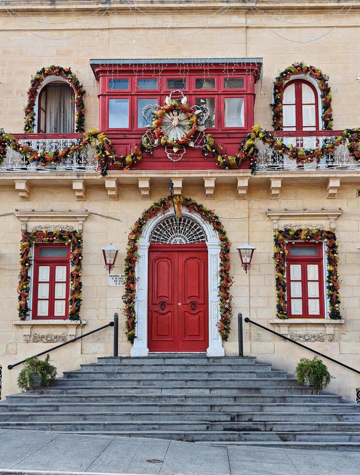 Paola, Malta,16.12.2024 - Close-Up of Historic Building with Red Door and Festive Christmas Garlands in Malta photo