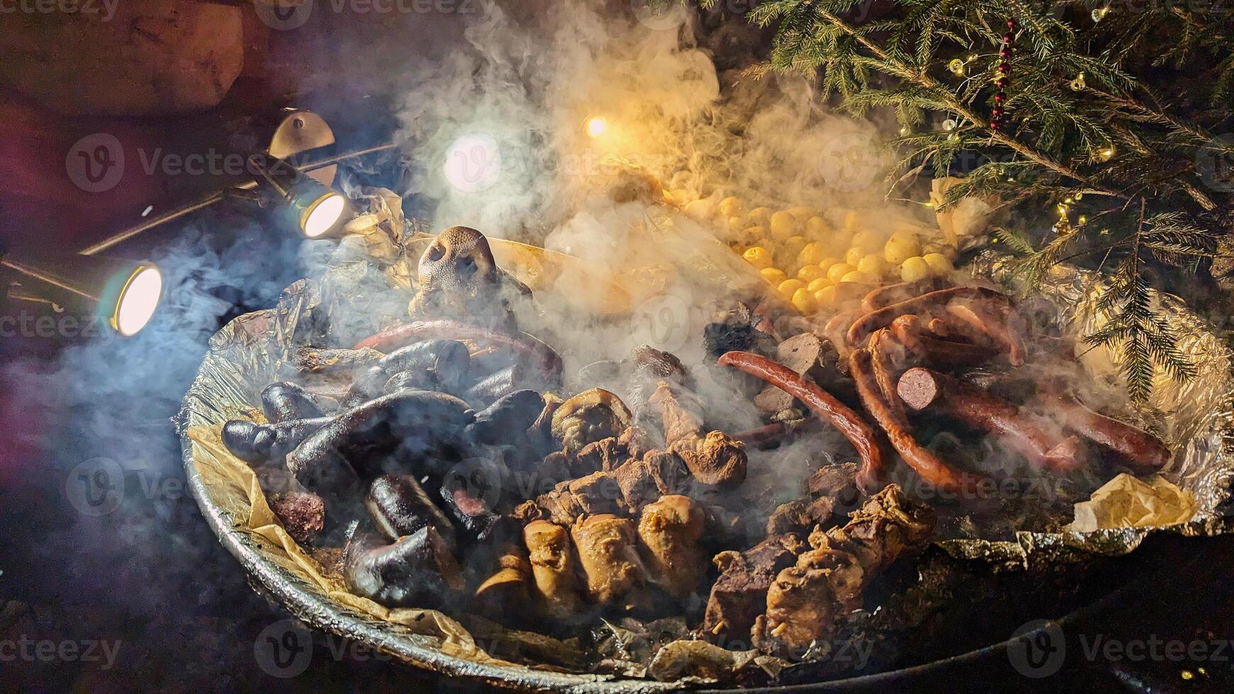 Traditional Smoked Meats and Potatoes on Open Fire at Christmas Market photo