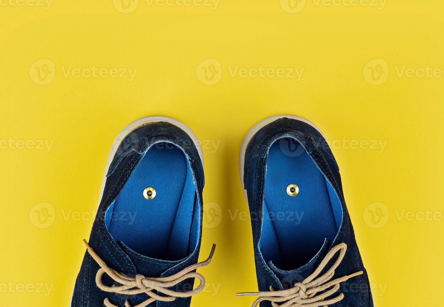 Blue Shoes With Push Pins Inside on Yellow Background With Copy Space photo