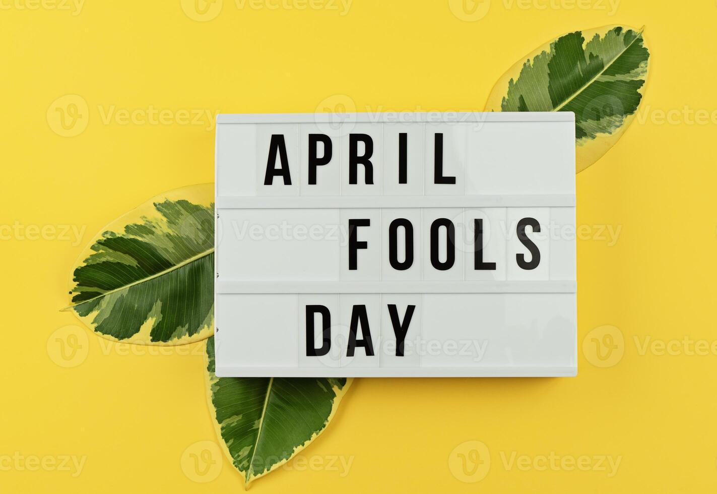 Lightbox Displaying April Fools Day With Green Leaves Against Bright Yellow Background photo