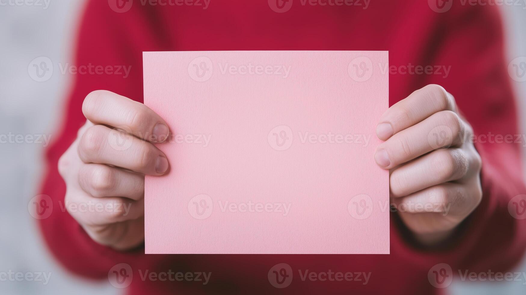 Hands Holding Blank Pink Card Against Red Sweater Background Reflecting Communication and Awareness Concepts photo