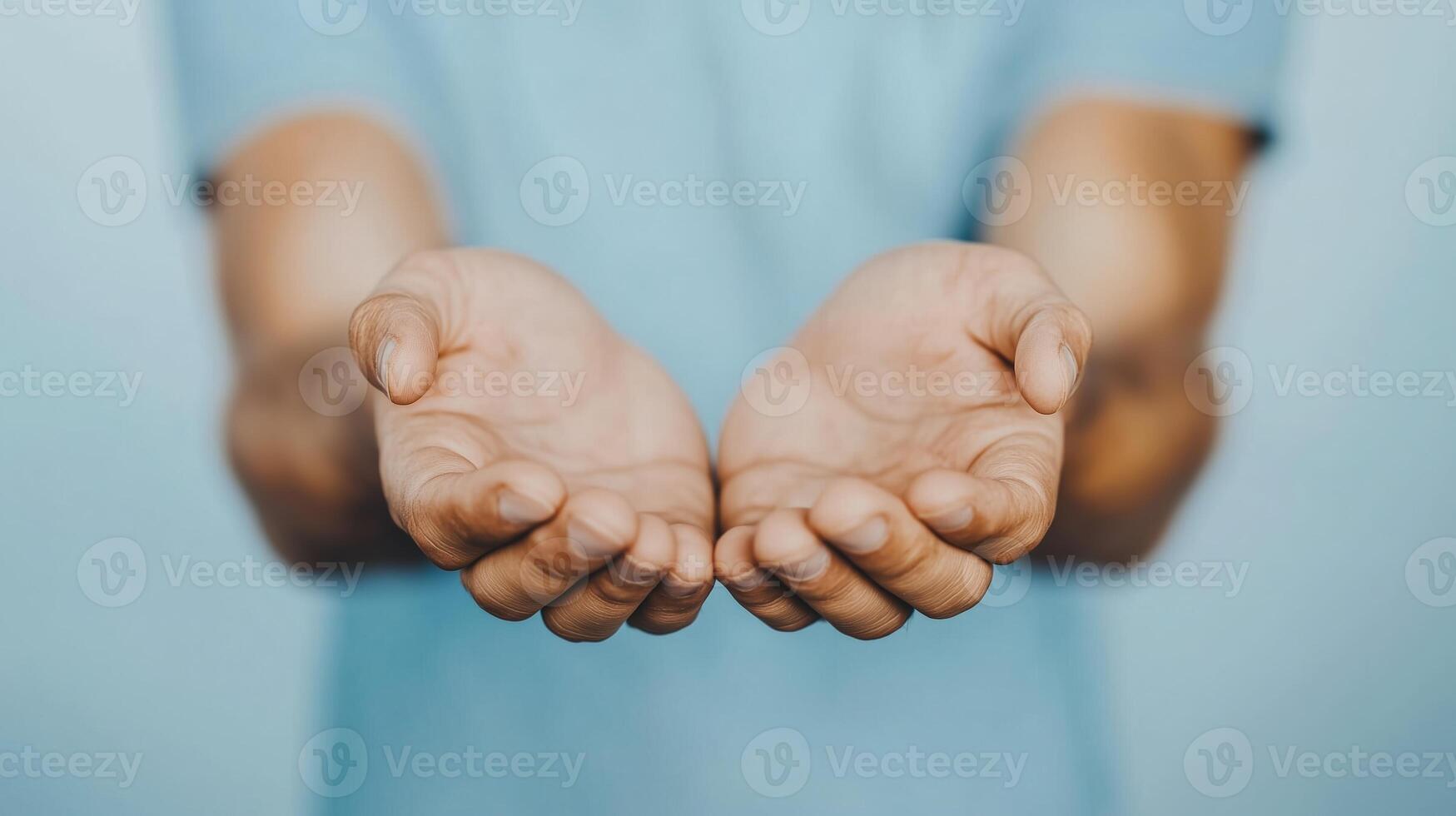 Close-up of open hands extended forward on a soft blue background. Concept of giving, receiving, and kindness photo
