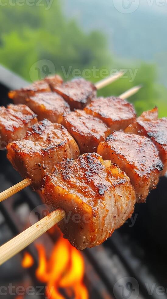Grilled Meat Skewers Cooking Over Open Fire Barbecue with Blurred Green Forest Background in Summer Outdoor Picnic Scene photo