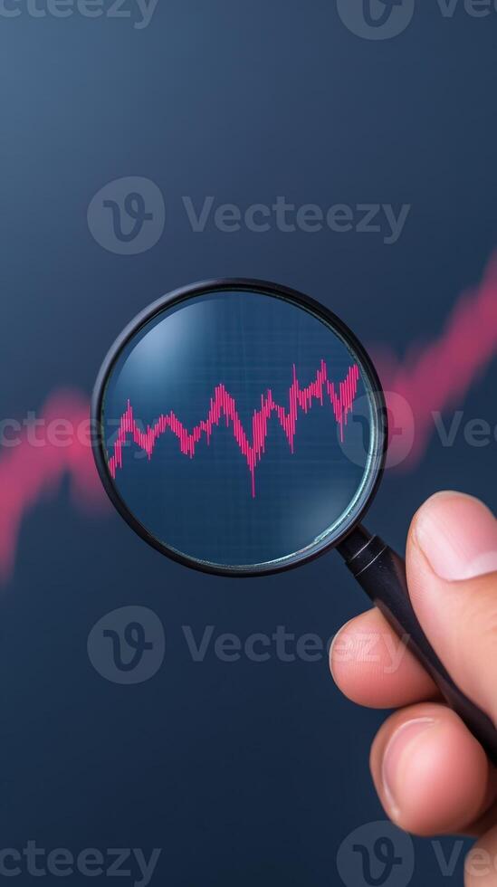 Hand Holding Magnifying Glass Over Digital Stock Market Displaying Red Graph on Dark Background for Trend Analysis and Financial Concept in Vertical Format photo