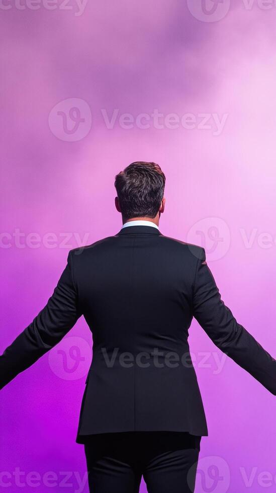 Motivational Speaker in Black Suit Greets Diverse Audience on Stage with Dynamic Purple Lighting Inspiring Energy and Connection Public Speech Conference Event photo