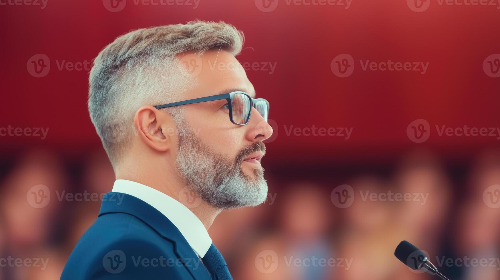Business Leader in Blue Suit Delivering Speech at Conference Podium to Engaged Audience in Professional Setting with Blurred Background and Microphone photo