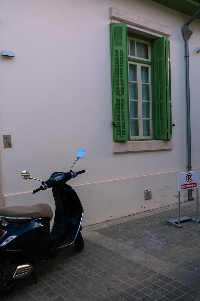 A quiet and hidden house with green shutters and motorcycle on the front of house in the historic part in the Cypriot town of Nicosia,Cyprus November 4,2023 photo