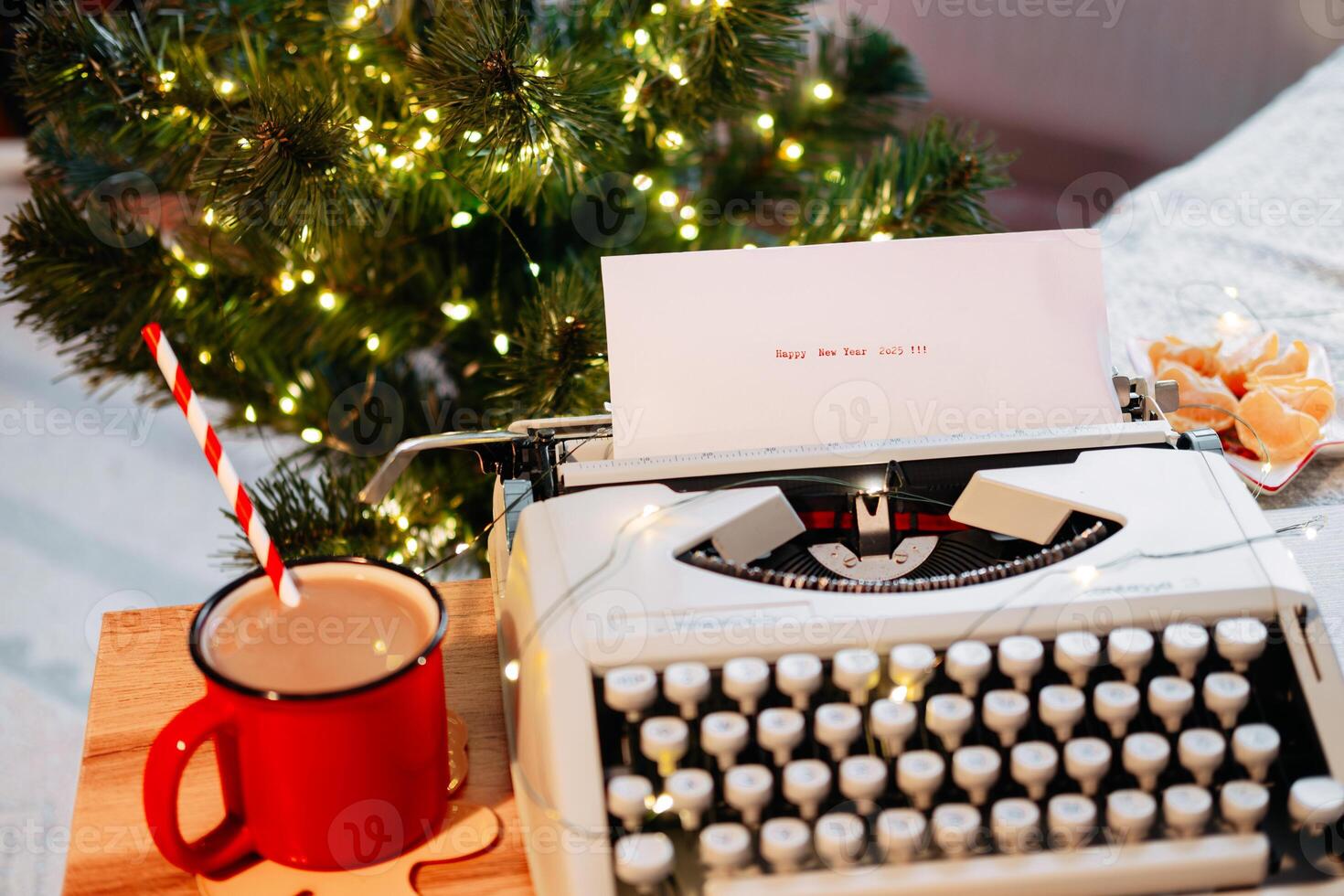 Typed on a typewriter-Happy New Year 2025, against the backdrop of a Christmas tree with garland and cocoa with tangerines on a wooden tray photo