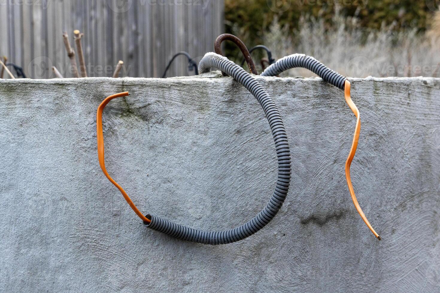 Orange wires with isolation scattered on earth among plants and soil, garden lightning photo