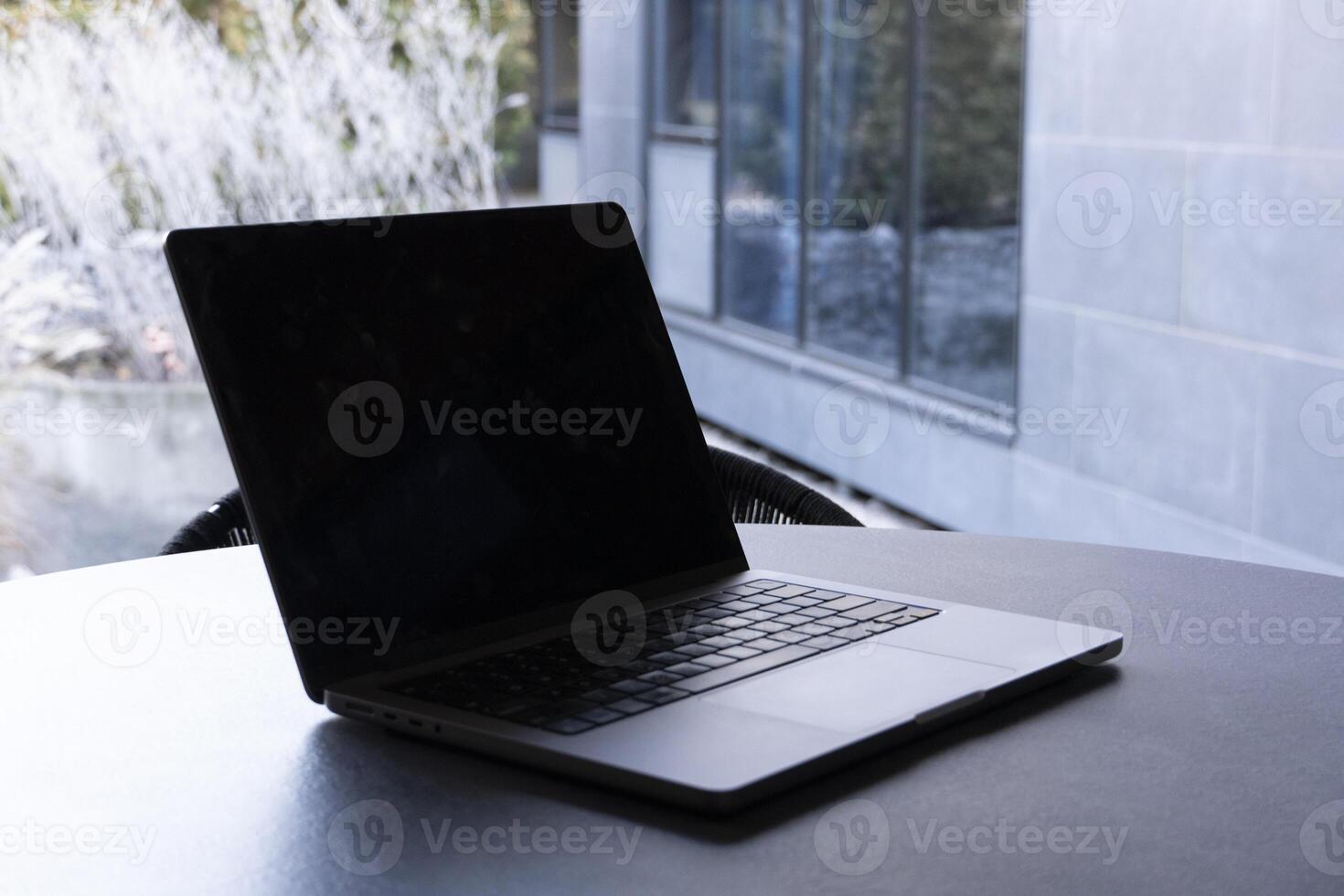 laptop on a round table with an outdoor background. Mockup design, for business, remote work, or modern workspace themes. photo