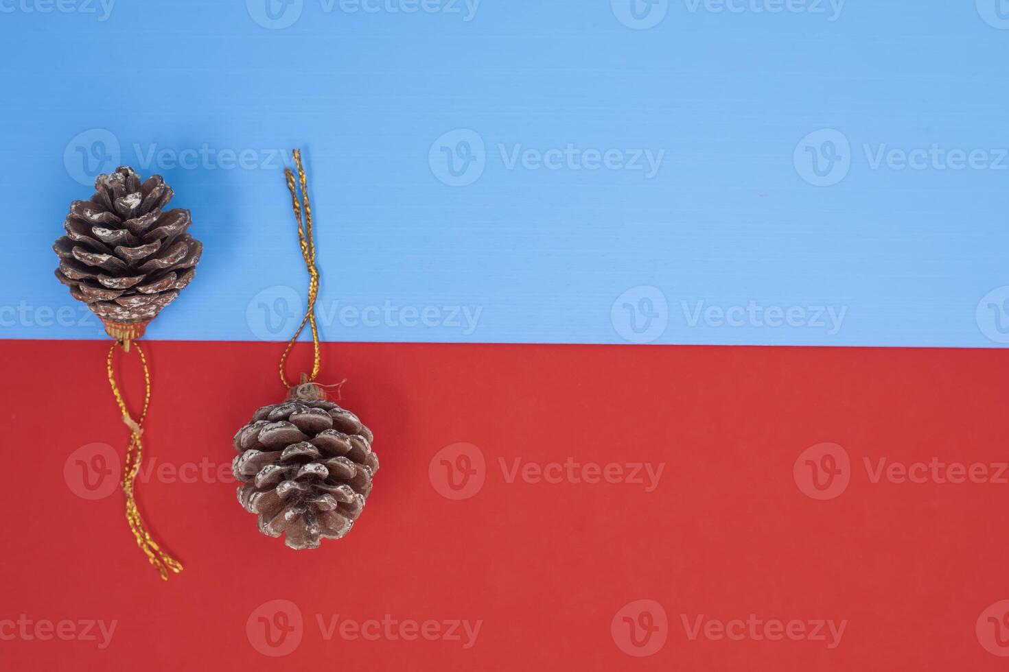 Brown pine cones with golden string loops on a vibrant blue and red background photo