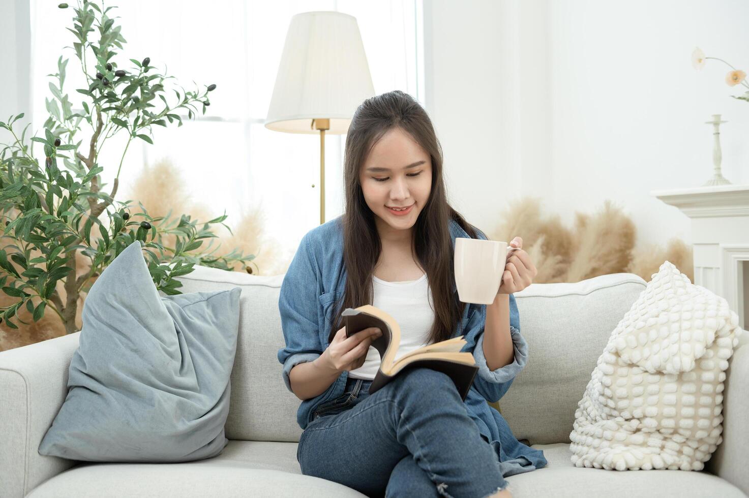 Young Asian woman enjoying reading book in living room at home photo
