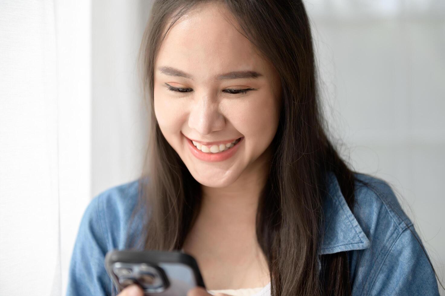 Young Asian woman enjoy using smartphone at home photo