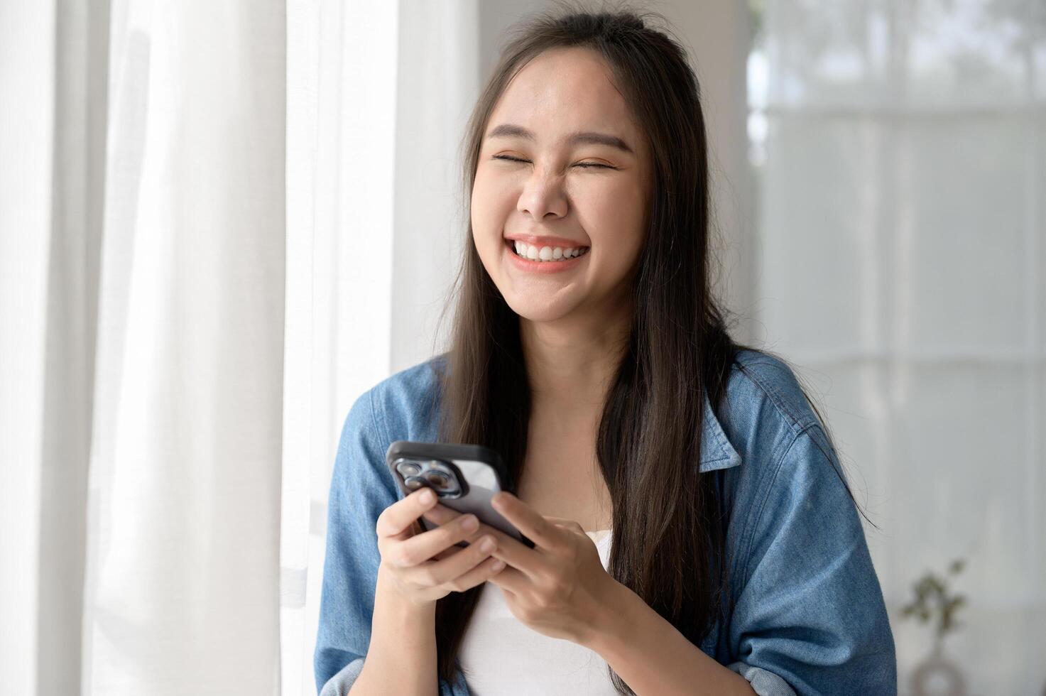 Young Asian woman enjoy using smartphone at home photo