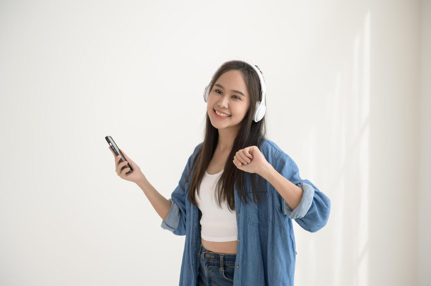 A young asian woman enjoying listening music and dancing over white background photo