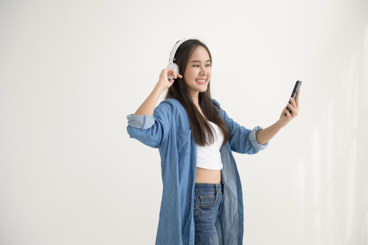 A young asian woman enjoying listening music and dancing over white background photo
